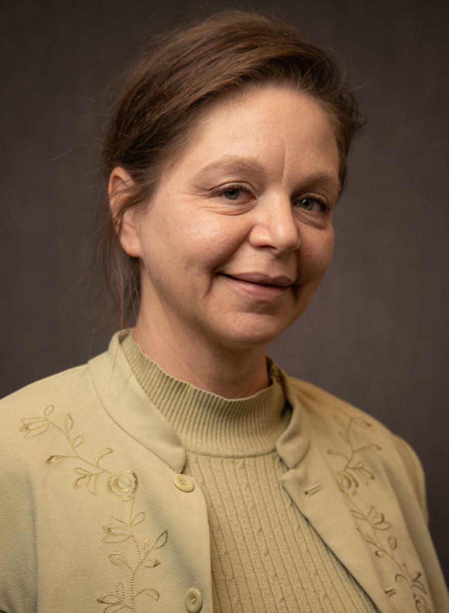 A Caucasian female with brown hair, Vianne Prowse is wearing a gold sweater as well as a gold dress jacket with flowered vine decorations running from the shoulder, across the chest area, down to the hem and a button enclosure.